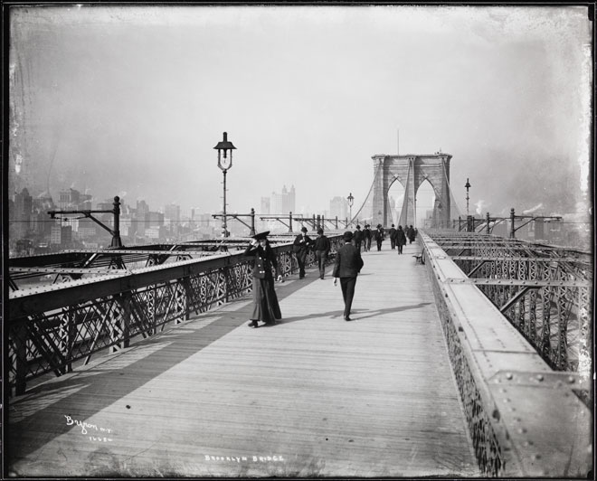 Uma fotografia em preto e branco de pessoas caminhando ao longo da ponte do Brooklyn em 1903