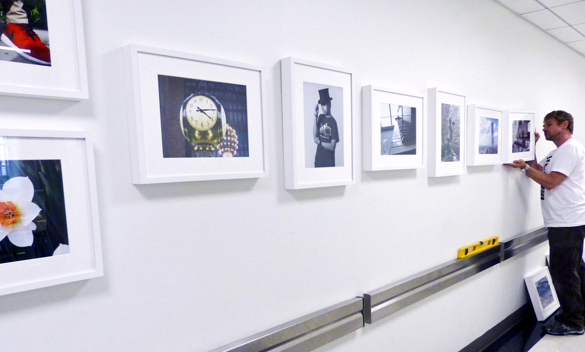 Un employé du musée installe les photographies de l'atelier I Spy sur le mur