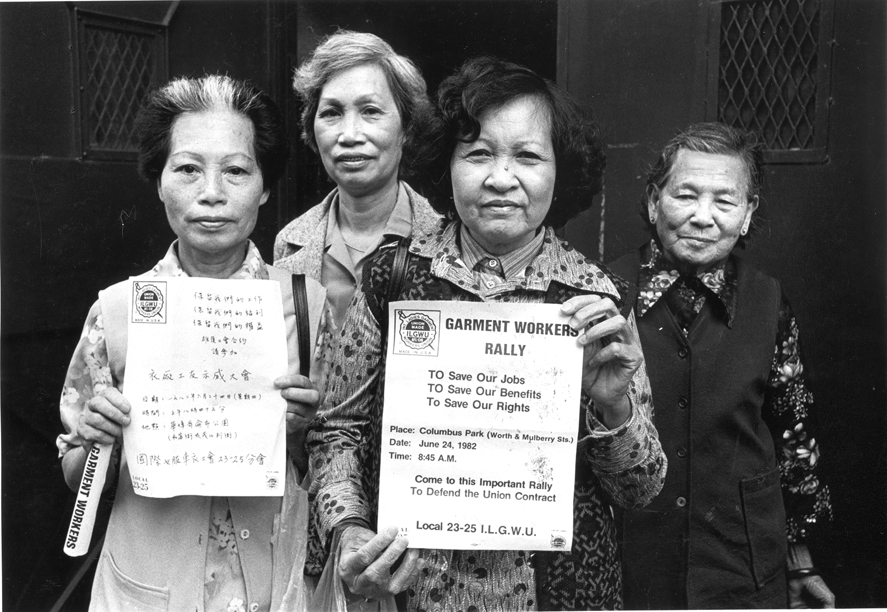 Membros do sindicato ILGWU Local 23-25 ​​olham diretamente para a câmera e exibem panfletos em inglês e chinês em apoio à greve contra as fábricas de roupas em Chinatown, na cidade de Nova York.