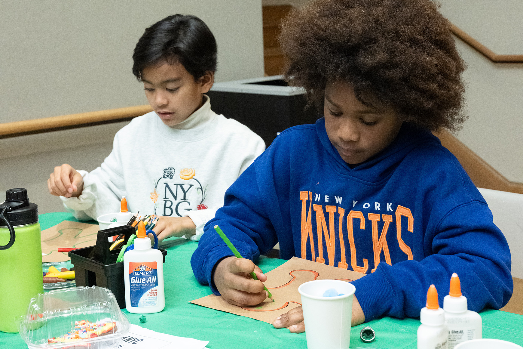 Two children creating an artwork with colored pencils.