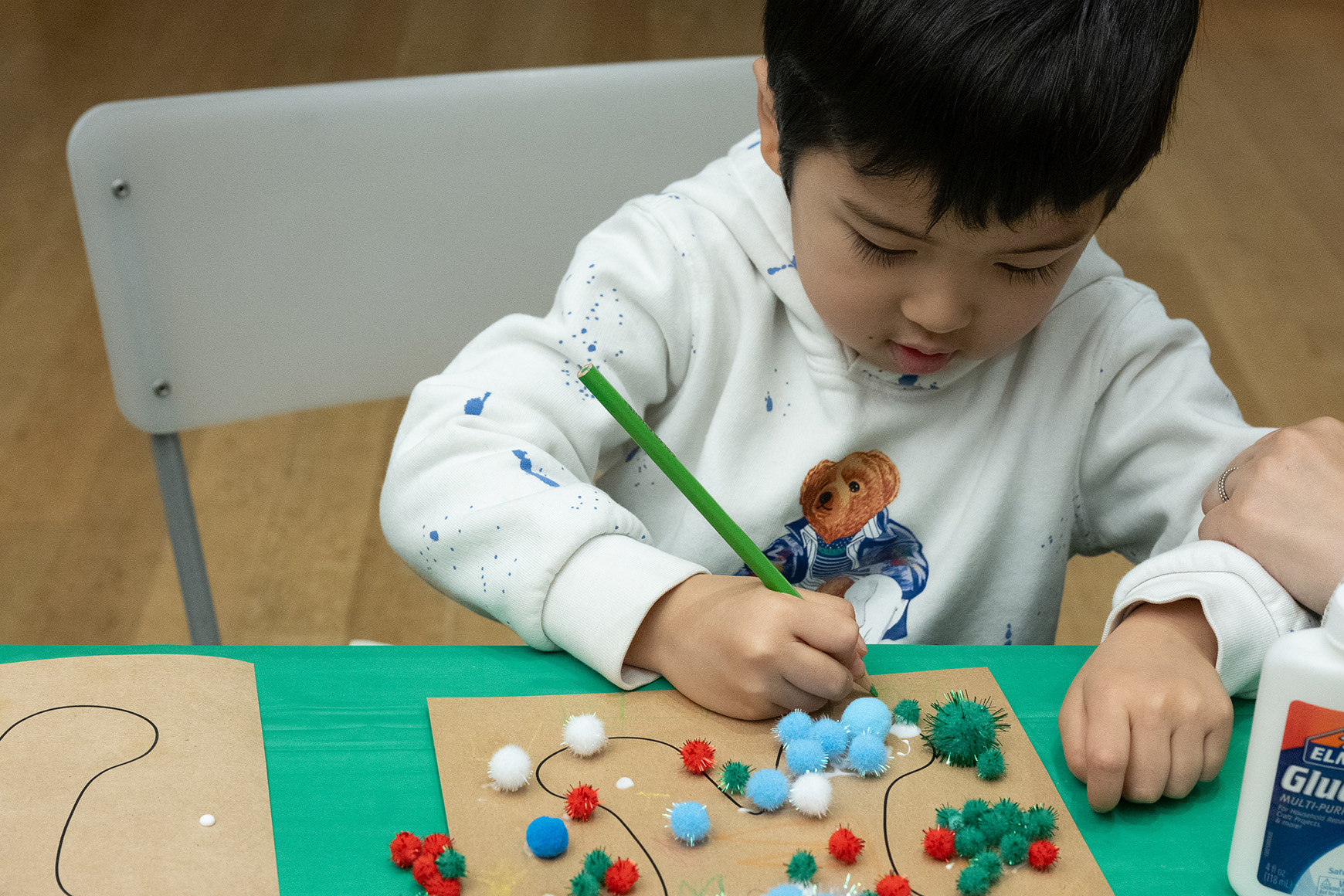 One child creating an artwork with colored pencils and collage.
