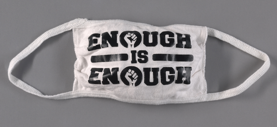 Face mask with "ENOUGH IS ENOUGH" in black text. The "O's" have a fist in the center of the circle.