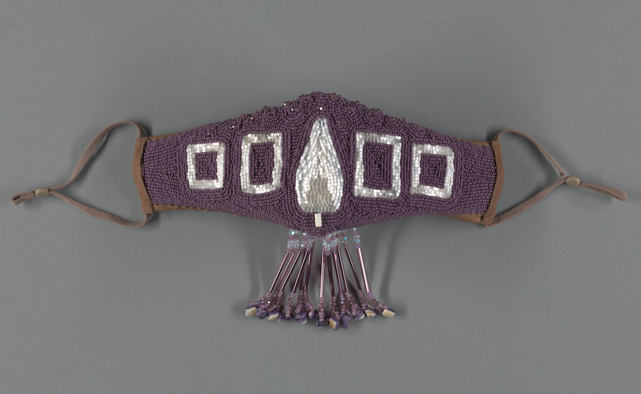 有串珠的紫色背景和白色串珠的设计做的面罩。 一个小条纹从中心垂下。
