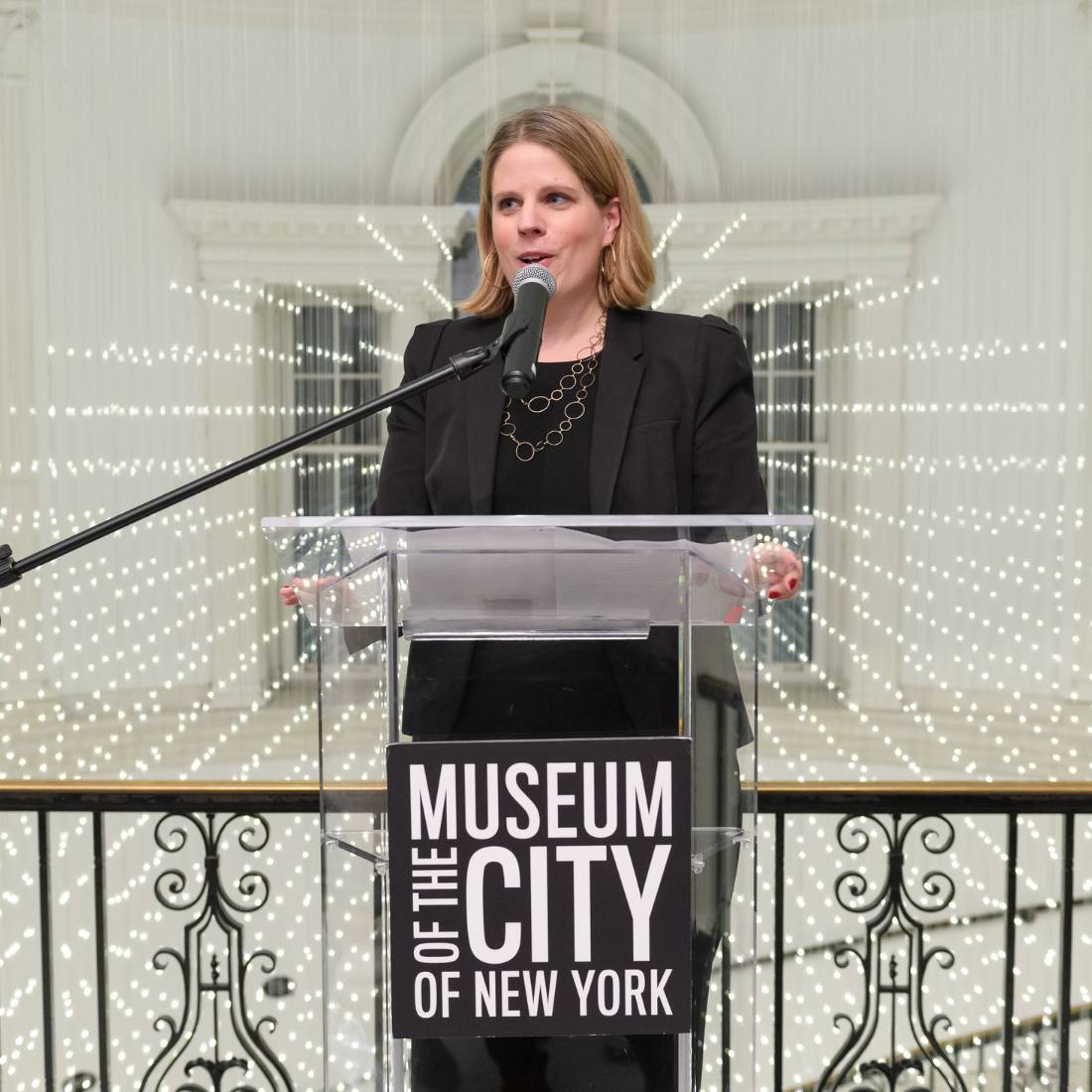 Imagen de la curadora Lilly Tuttle en un podio transparente con el logotipo de texto "Museo de la Ciudad de Nueva York"