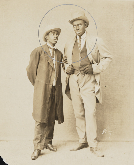 Two African-American gentlemen in suits stand next to each other