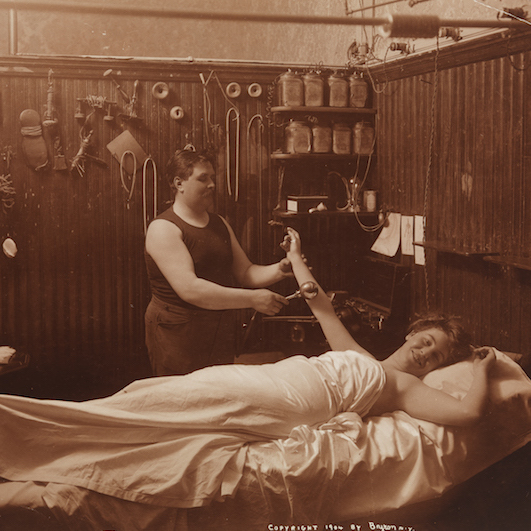 A woman reposing, receiving some sort of massage therapy in a Turkish bath.