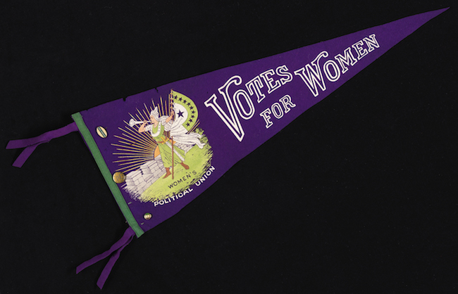 「女性参政権」と「女性参政権」で上映された紫色のウールのフェルトペナントには、「女性参政権」と「女性参政権」を宣言する金属製のバッジが貼られています。