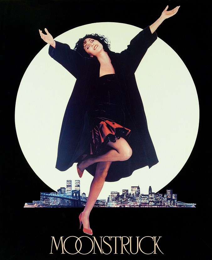 Cher holds her arms up in the air in front of a full moon. 