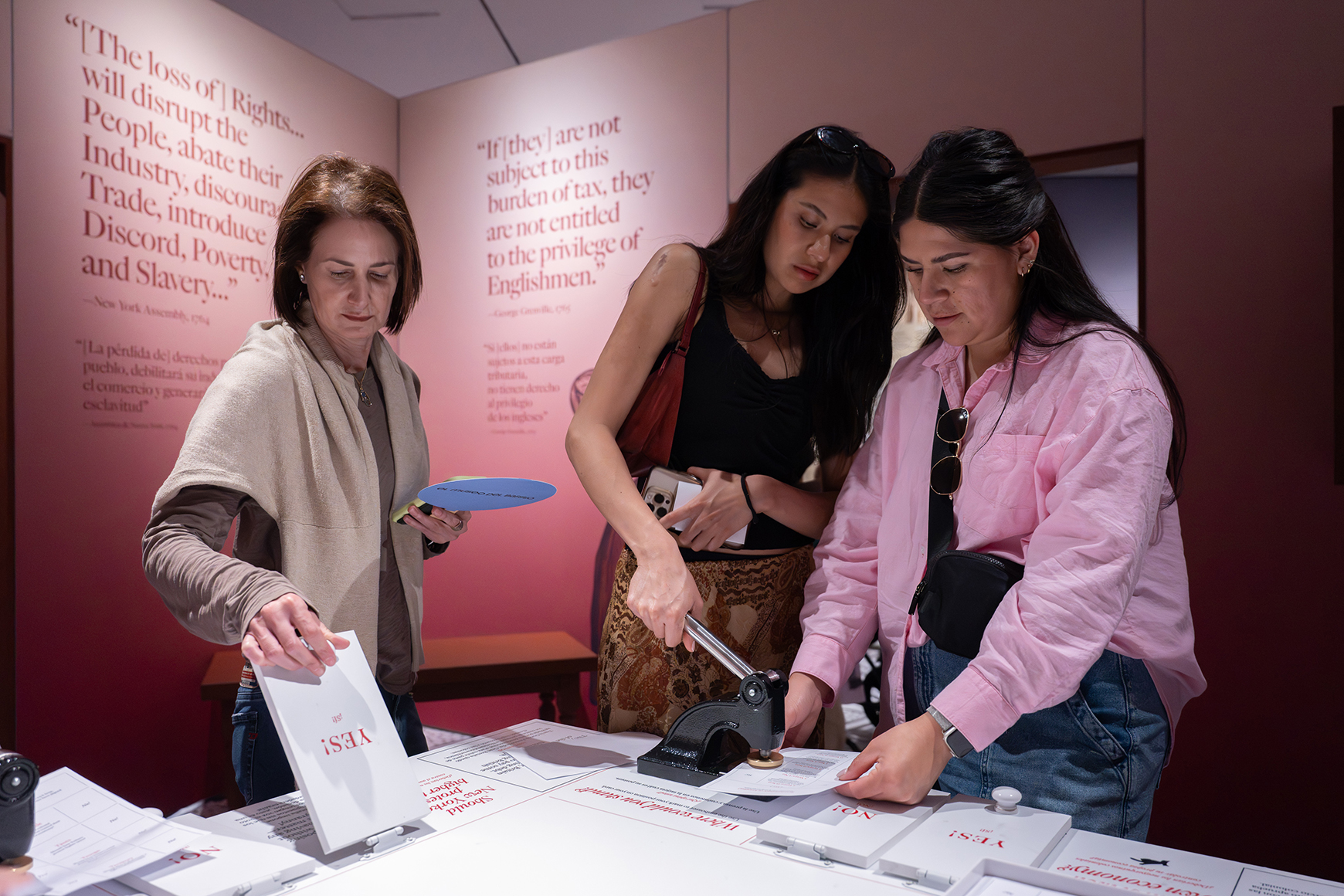 Three people use an interactive questionnaire in a gallery with red walls.