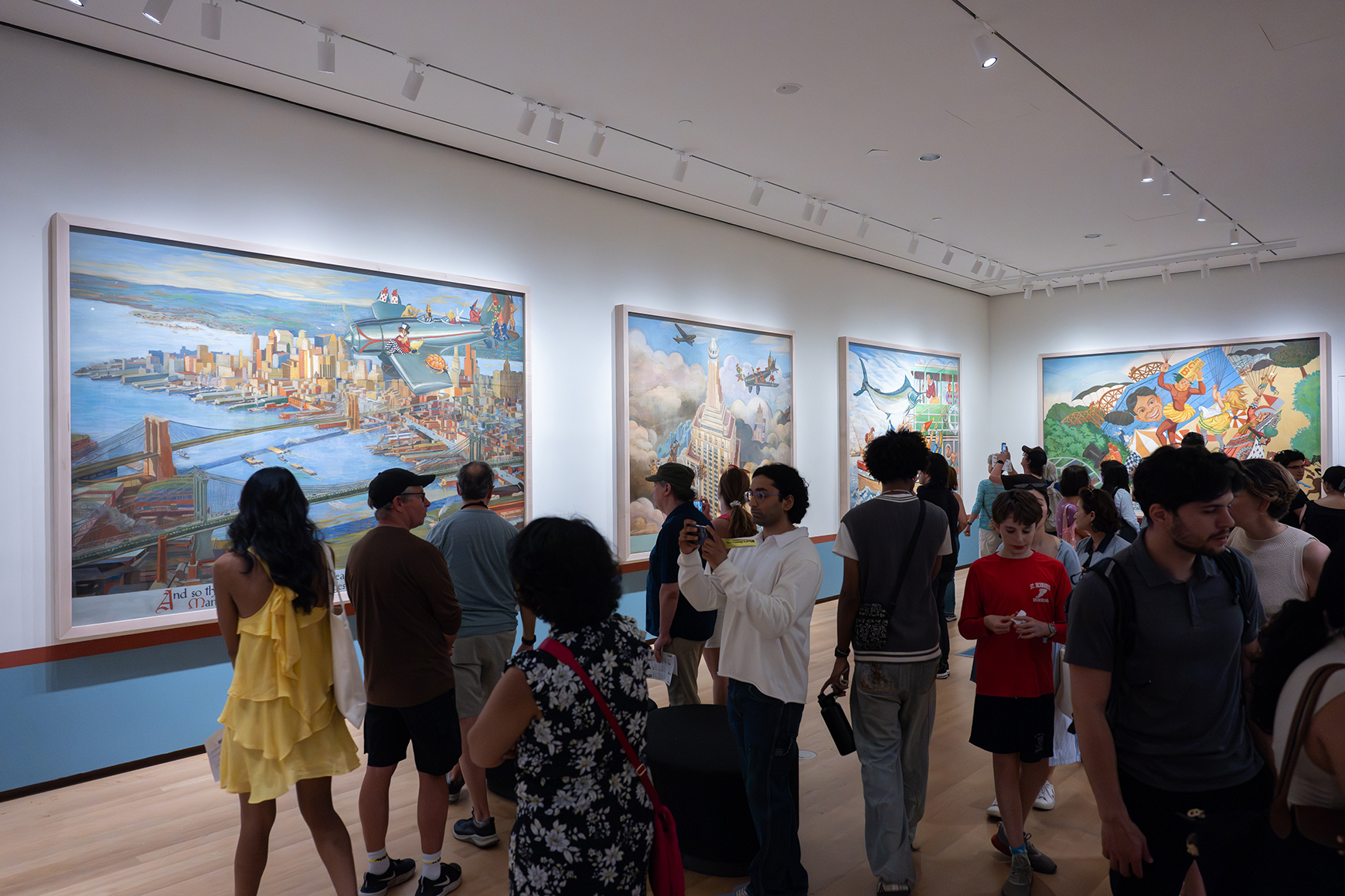 A crowd of people in a gallery with large painted murals