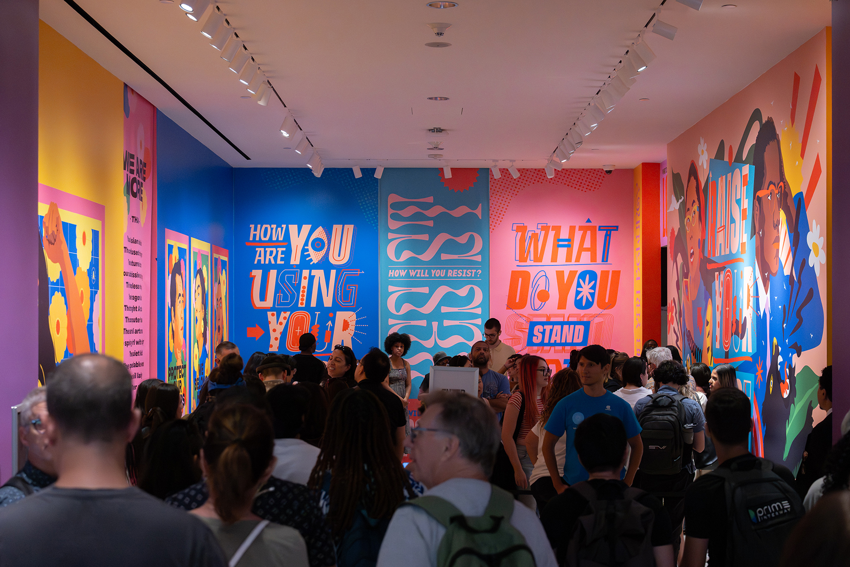 A crowd standing in a colorful gallery from the exhibition Activist New York.