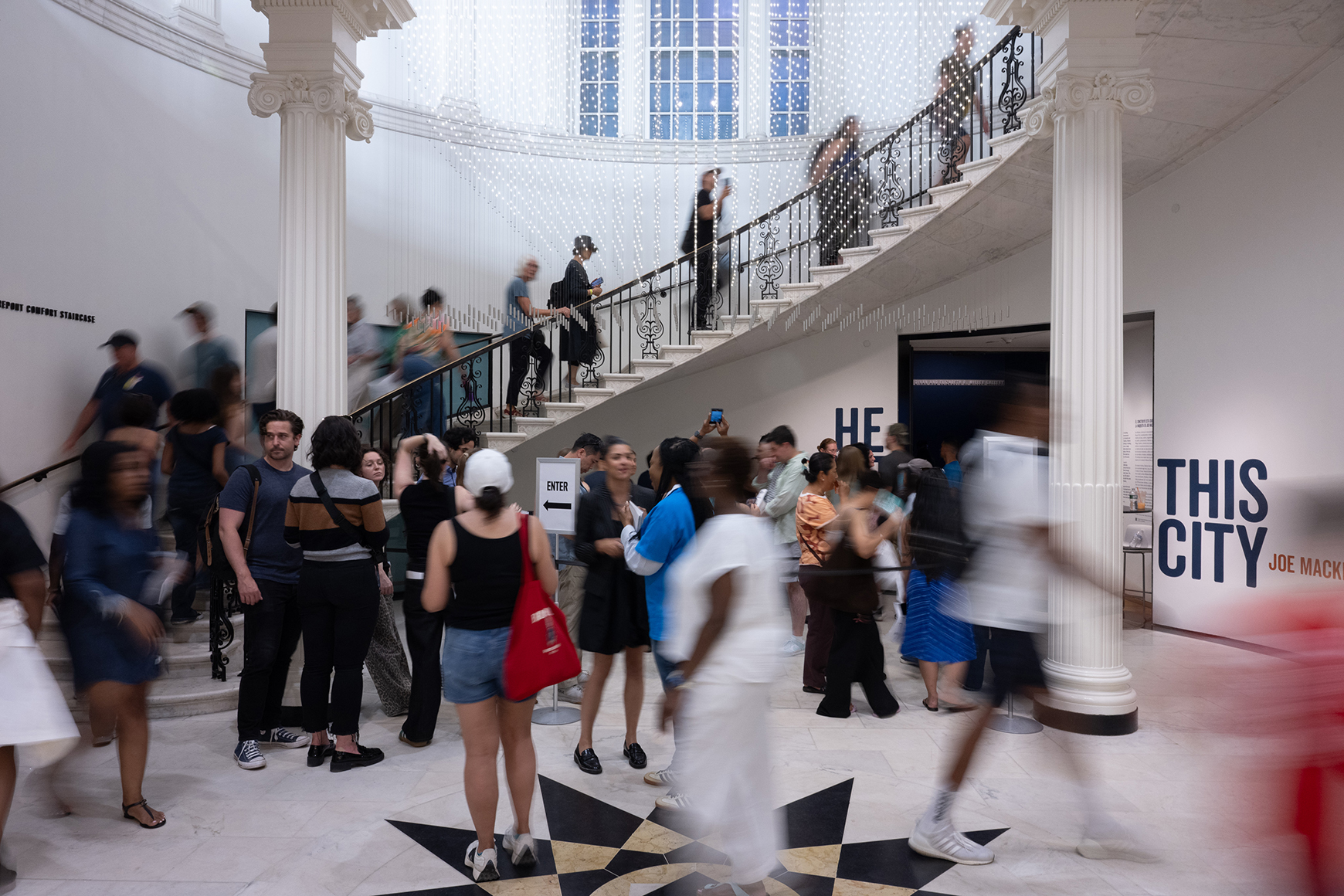 A crowd of people ascending a marble spiral staircase.