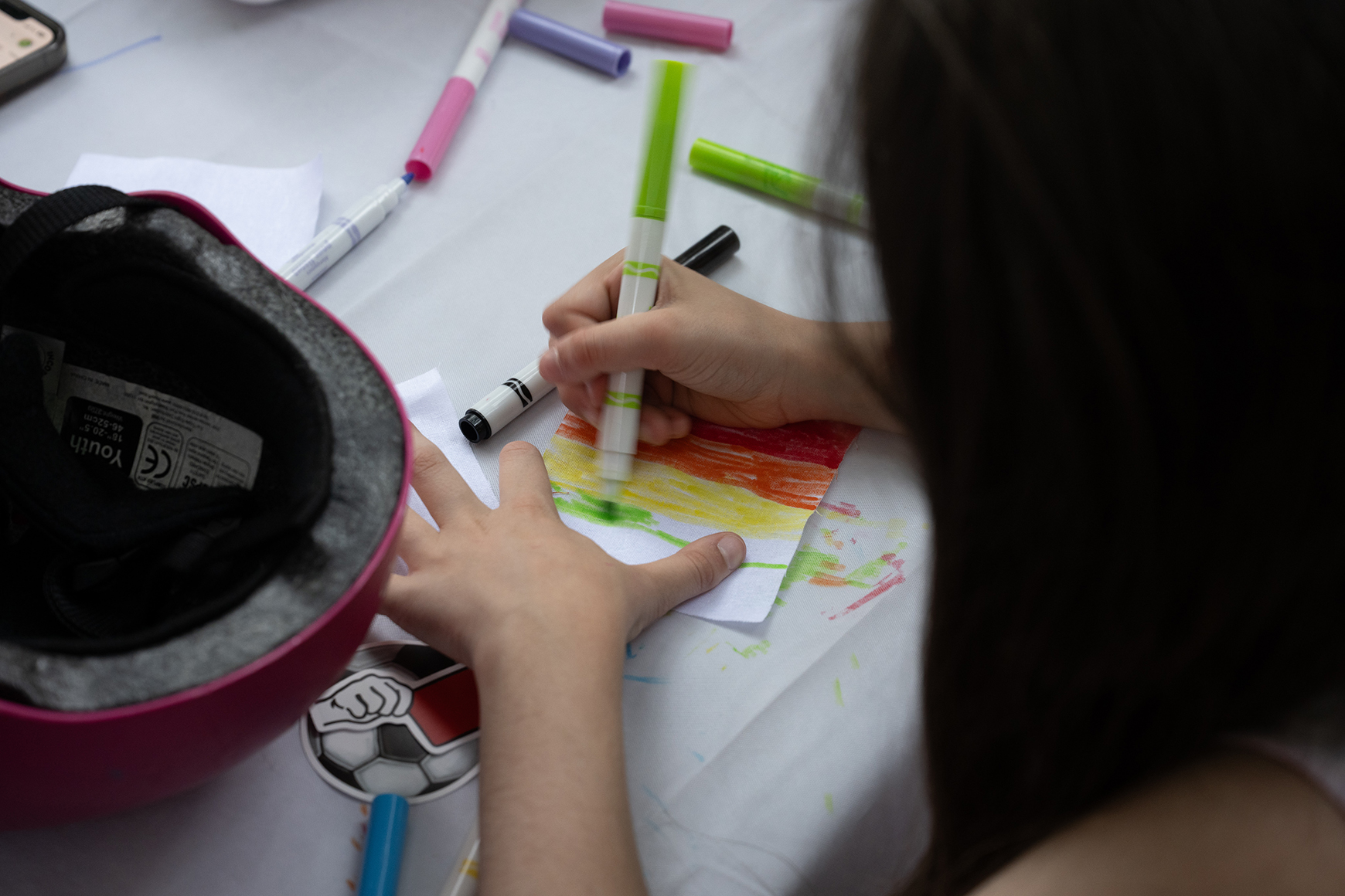 A child creating an artwork with markers.