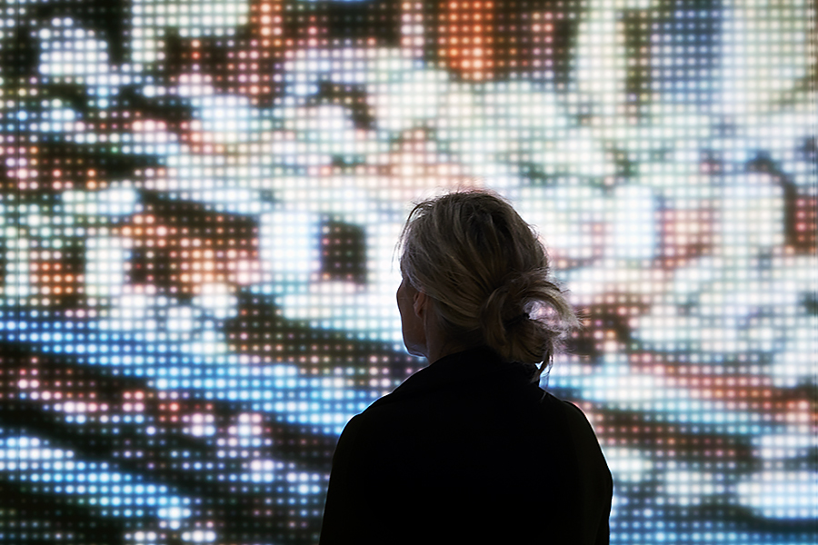 Individual silhouetted against a digital screen