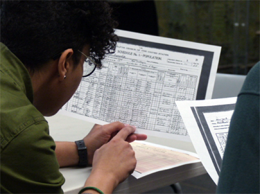 A teacher examines a completed 1900 census form in a workshop comparing the 1900 and 2020 census