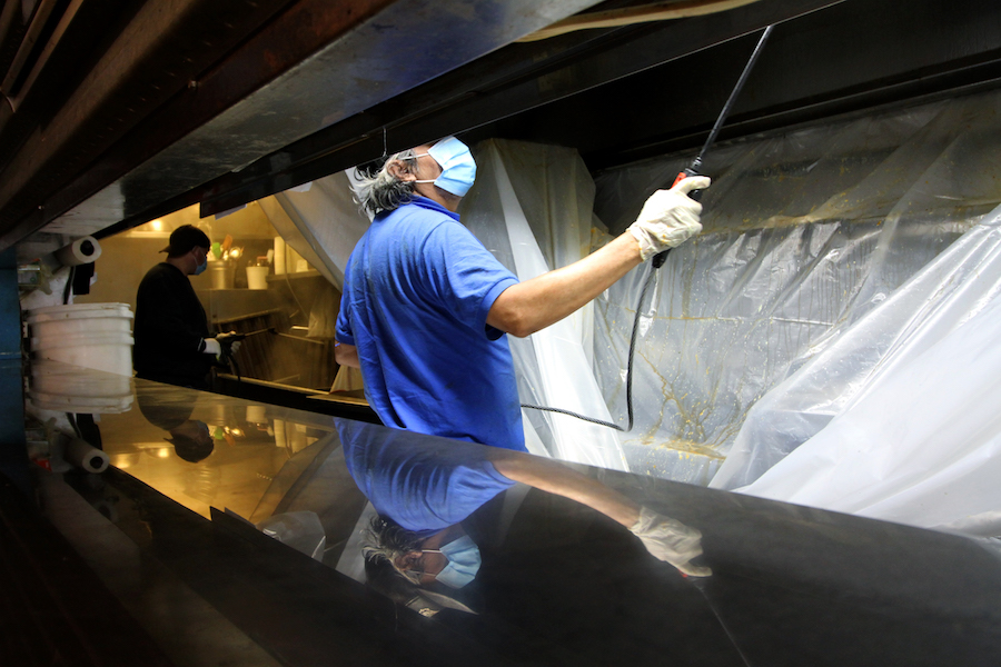 レストランの労働者は、ジープニーのキッチンで新しいCovid-19狭窄を使用して清掃します。