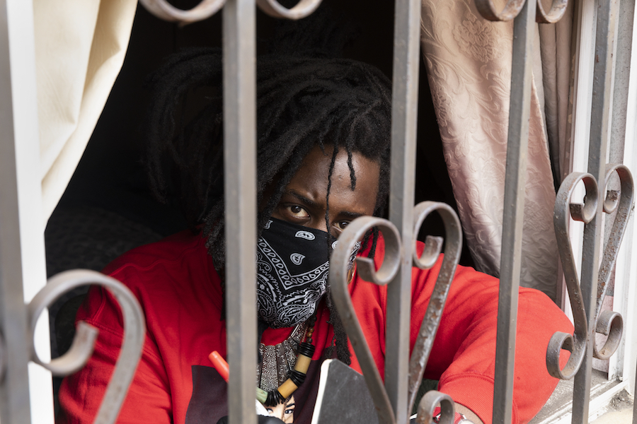 A man in a bandana sits behind a wrought iron grating 