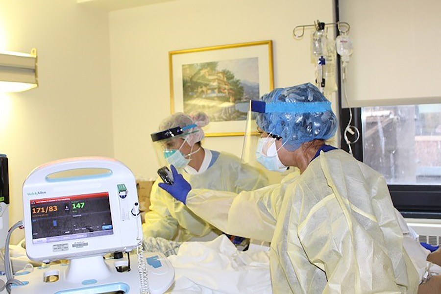 A medical worker holds a phone for a dying patient.