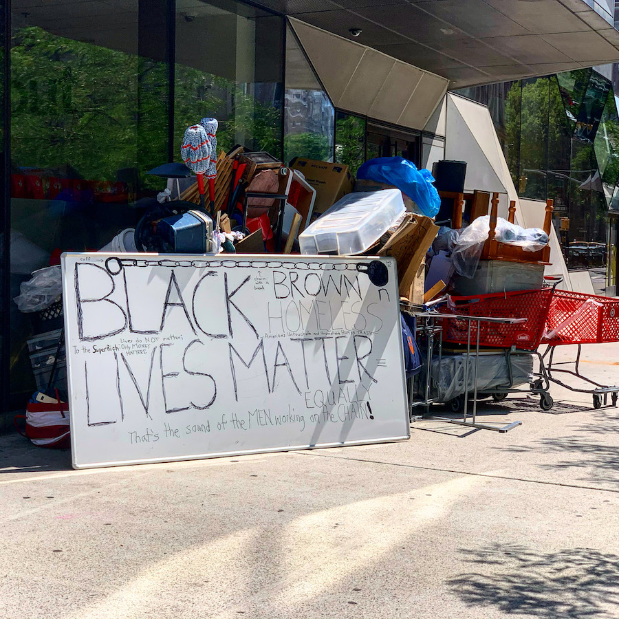 Protest sign in front of a homeless encampment.