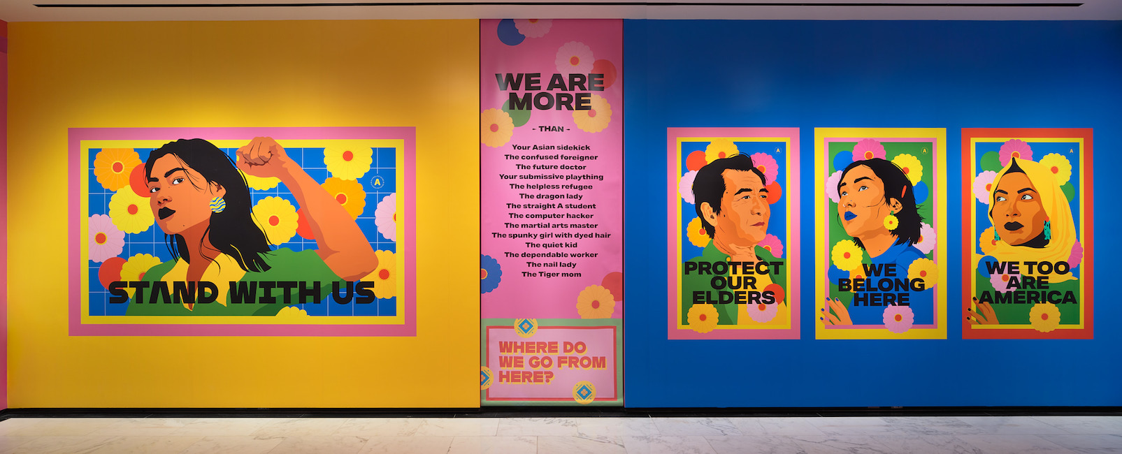 Installation shot of "Raise Your Voice," showing vibrant, colorful drawings of individuals with text.