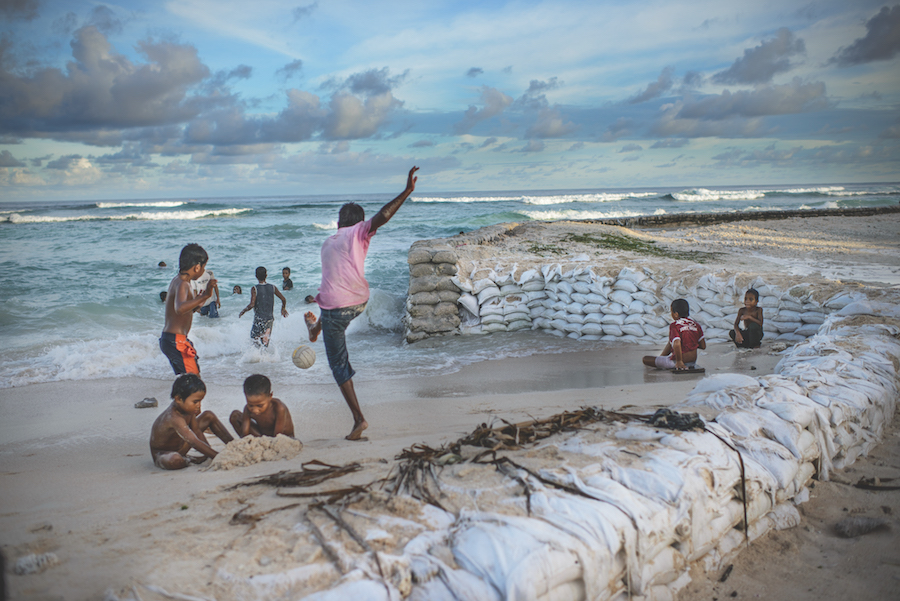 Children play on the beach where sandbags have been placed to try hold back the ocean at Temaiku, a vulnerable village on South Tarawa.