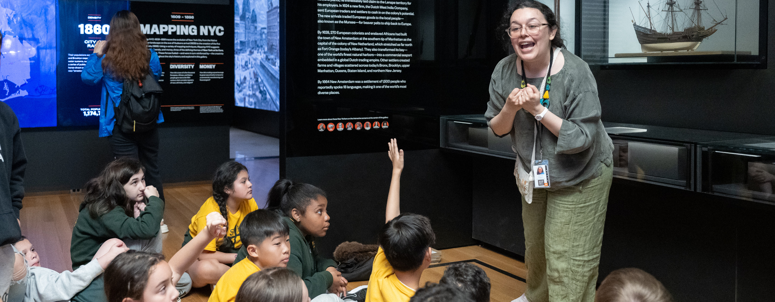 Educator teaching students who are seated on the floor in a gallery
