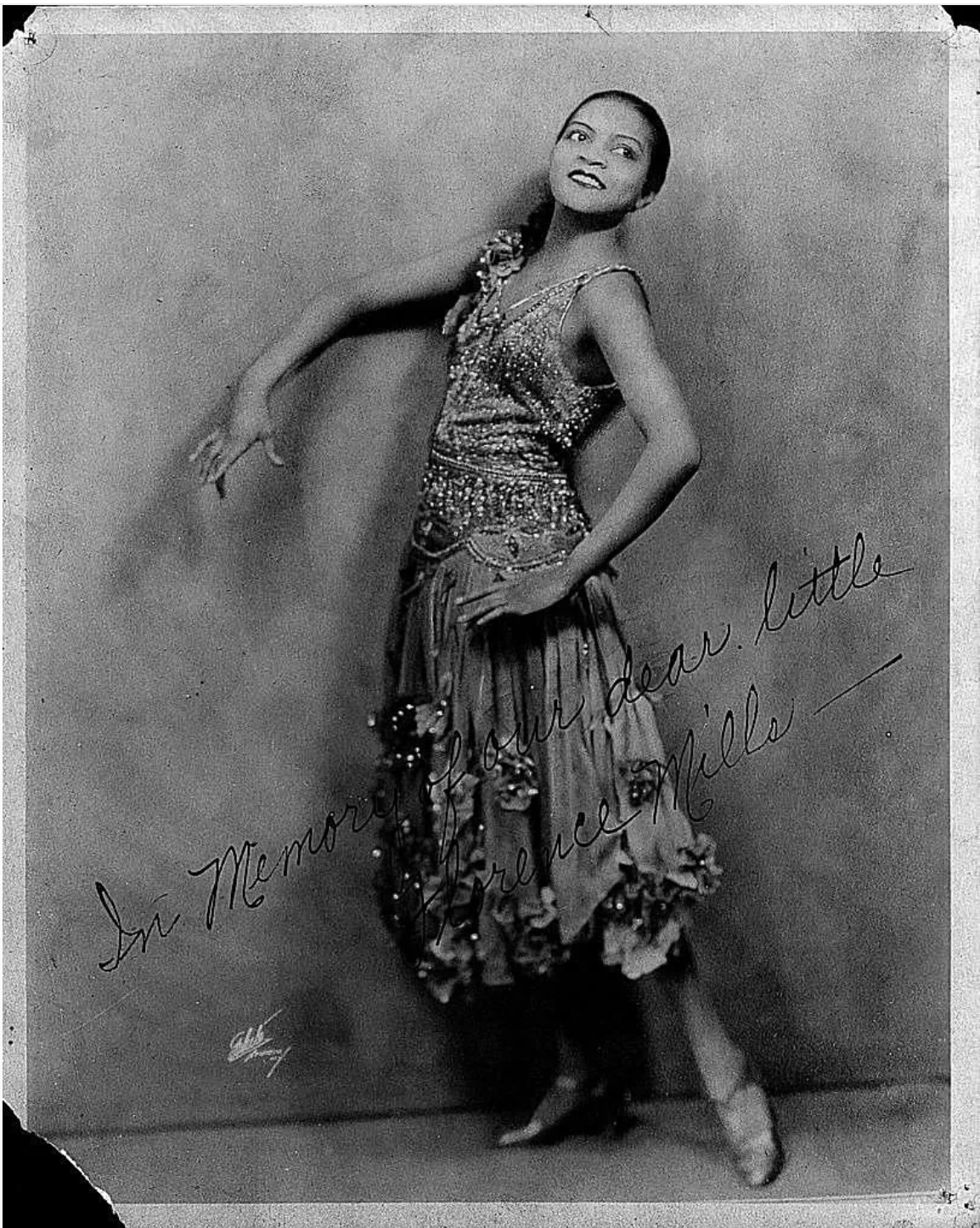 A woman poses against a backdrop in a long dress. 