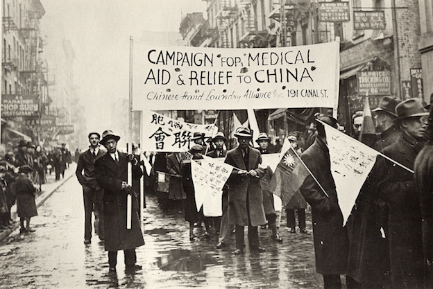 Desfile de trabalhadores da lavanderia chinesa com uma placa que diz "Campanha por ajuda médica e alívio para a China"