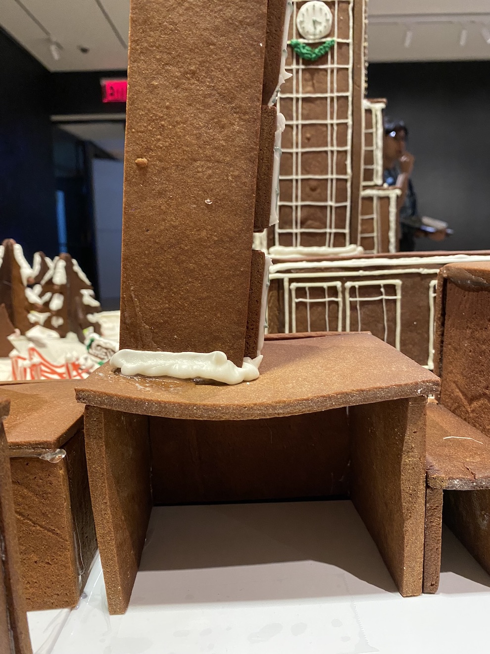 Gingerbread display of Madison Square Park in mid-installation. The roof section show in the display is beginning to sag.