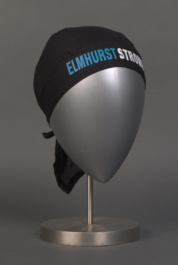 Casquette de gommage noire avec les mots "Elmhurst Strong" en bleu et blanc.