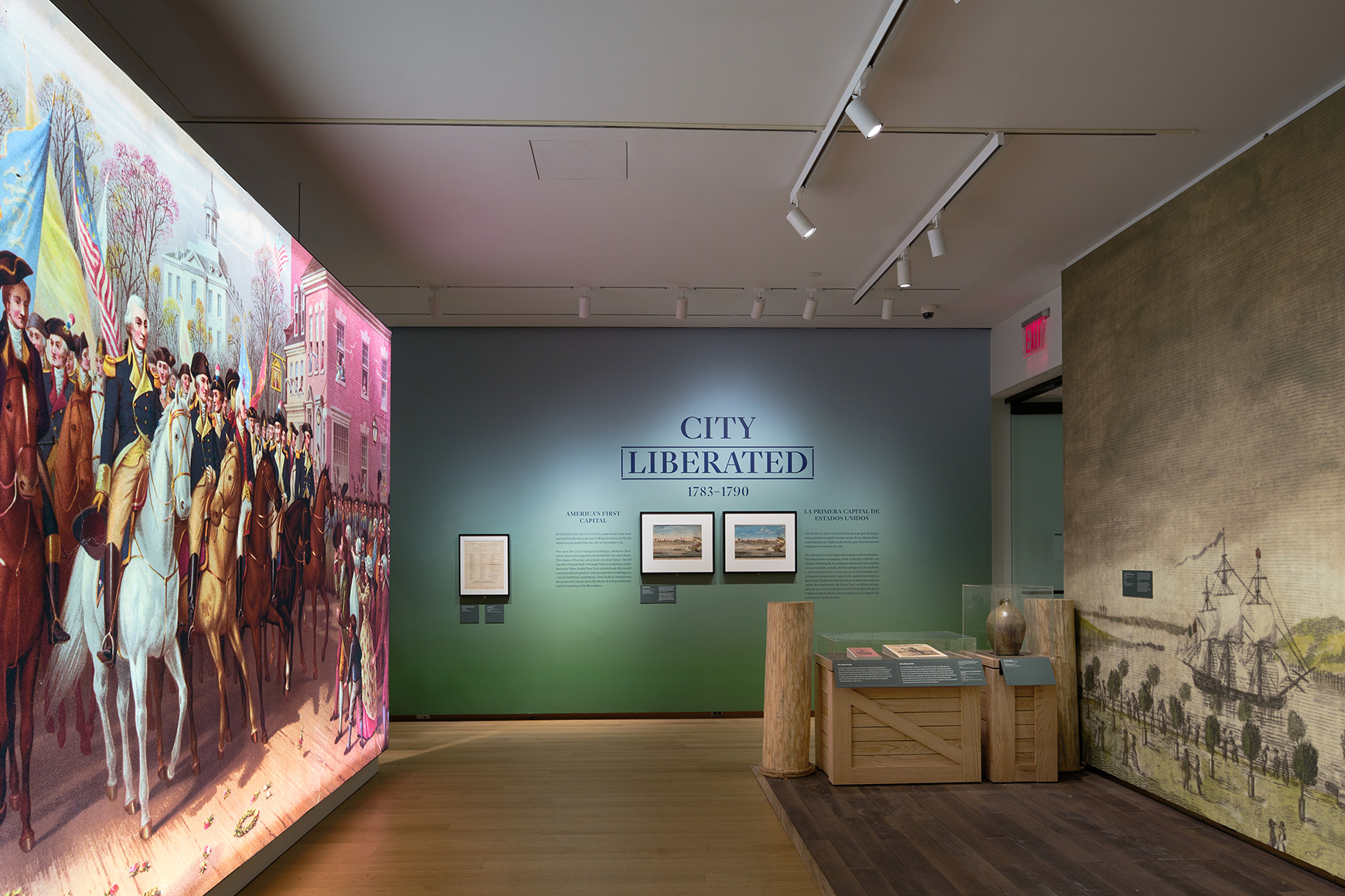 Installation view of the galleries, showing a large illuminated painting, objects in cases, and wall text saying, “City Liberated.”