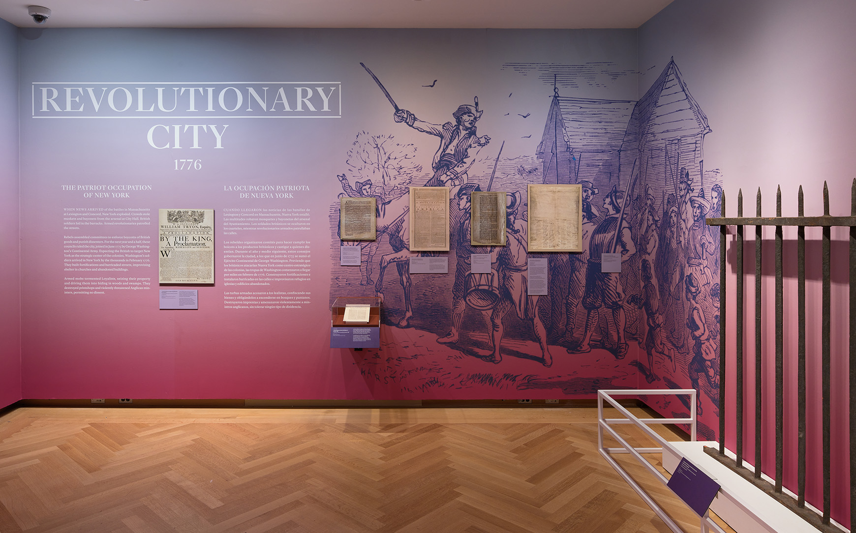 Installation view of the galleries, showing artwork on the walls and a large section of a historic fence.
