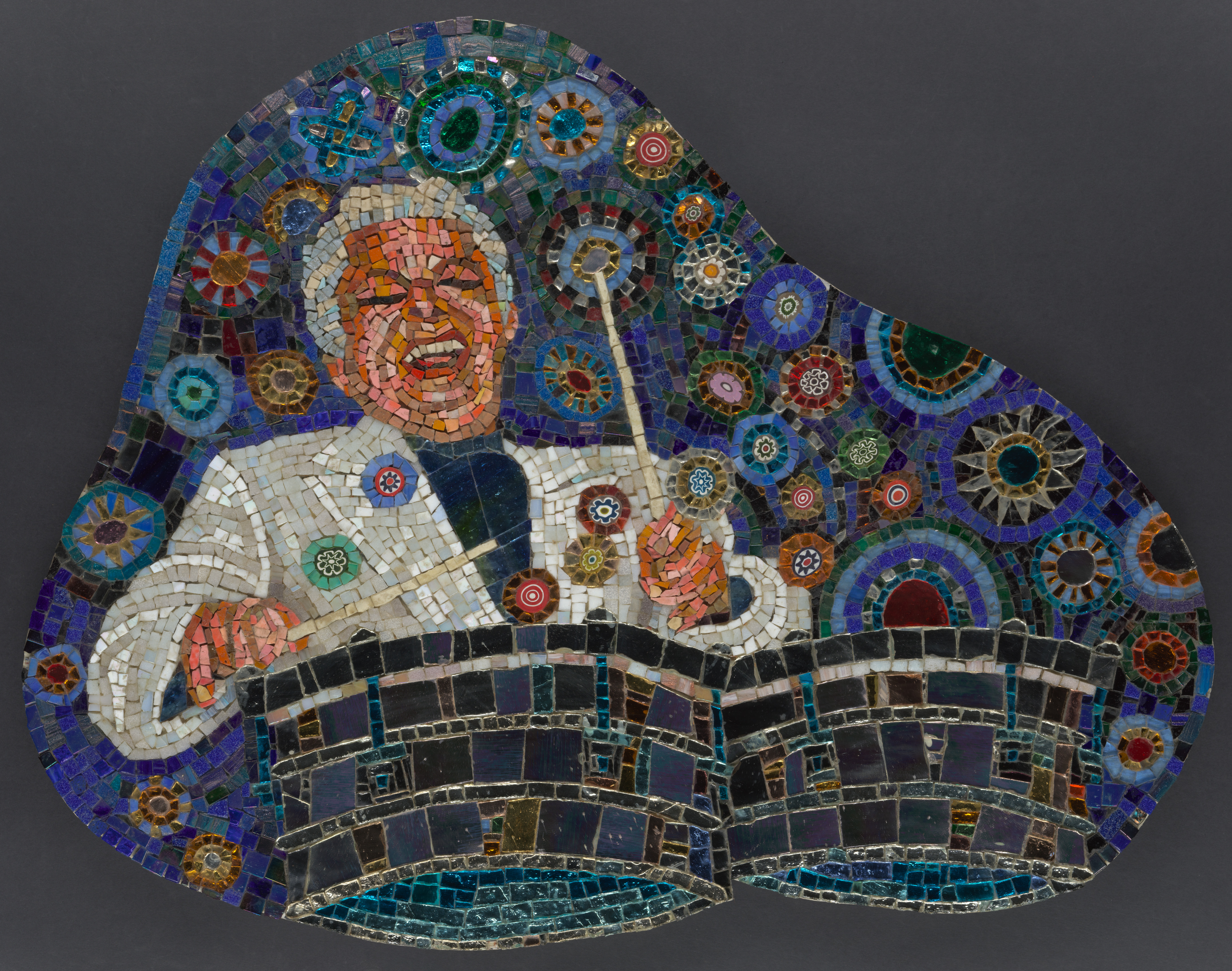 Une image d'une mosaïque représentait le célèbre musicien Tito Puente avec un sourire exubérant jouant joyeusement de la batterie sur un fond bleu rempli de cercles multicolores.