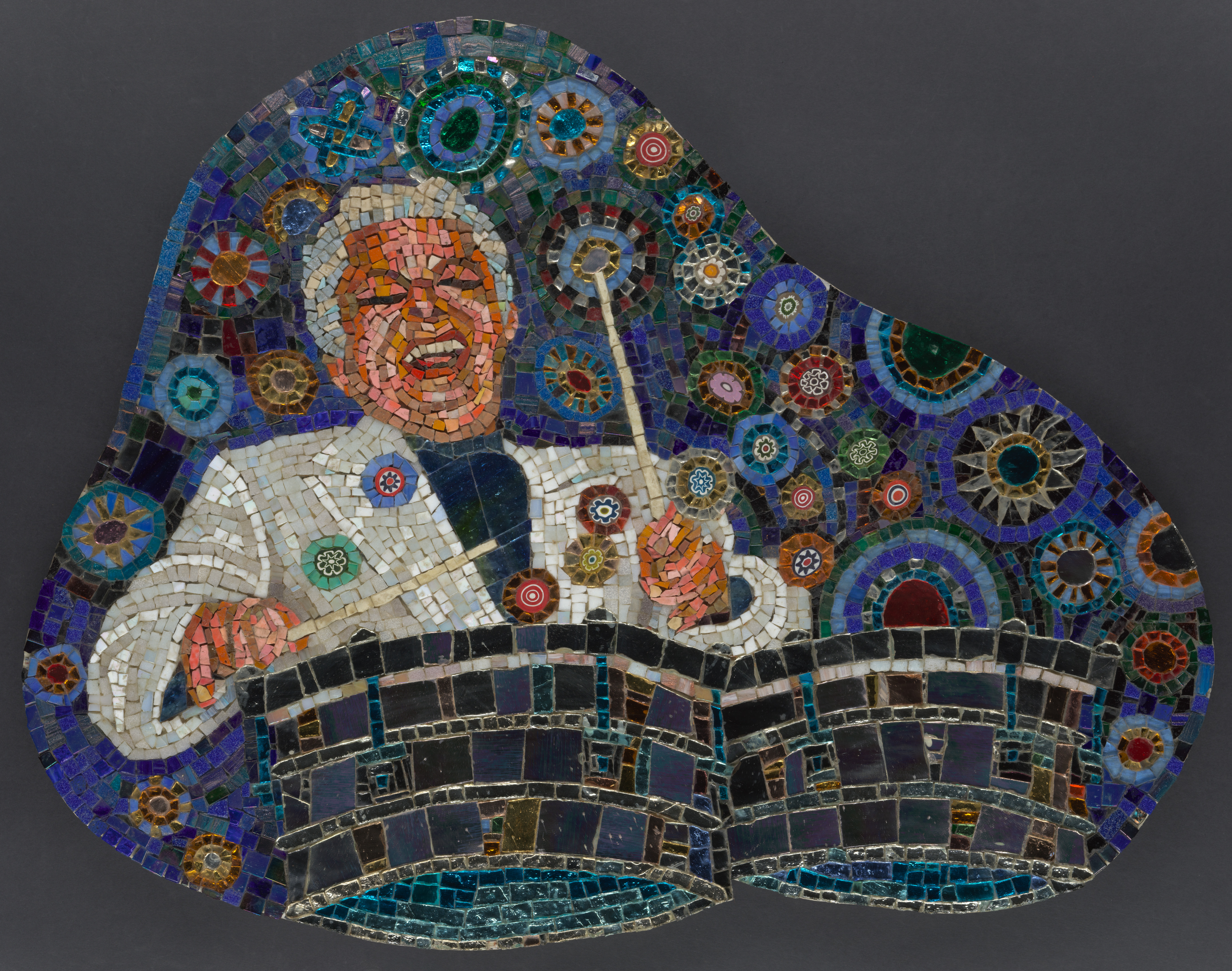 An image of a mosaic featured famed musician Tito Puente with an exuberant smile joyfully playing drums with a blue background filled with multicolored circles.