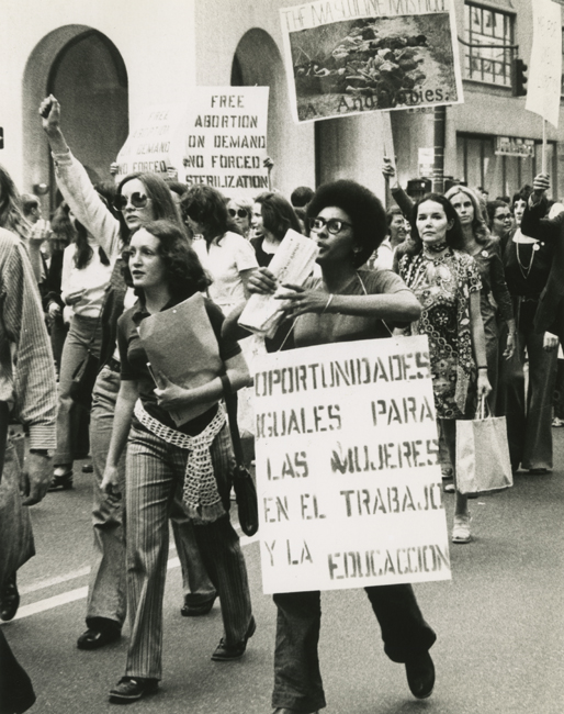 Las mujeres marchan en las calles, algunas con carteles, como parte de la Marcha de la huelga de mujeres por la igualdad