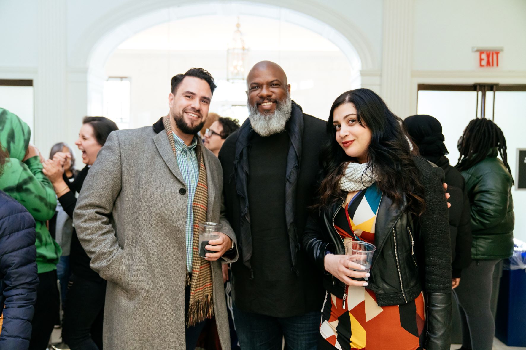 Two men and a woman pose with drinks.