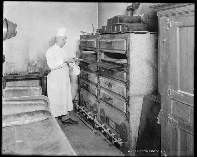 A photo by Wurts Bros. (New York, NY) of a restaurant chef using a bread oven.