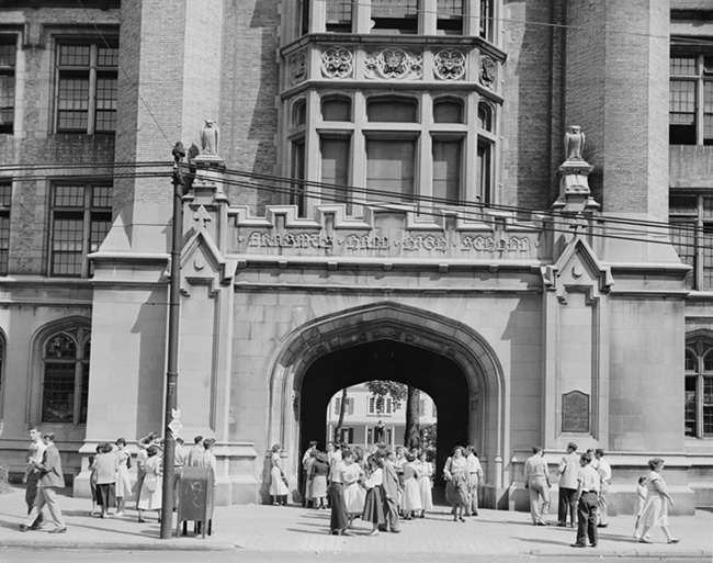 Exterior of Erasmus Hall High School with students hanging out in front.