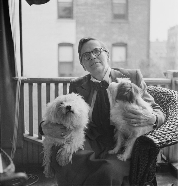 Florence Ripley Mastin sentada em uma varanda com dois cães no colo.