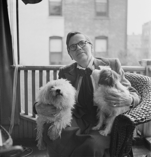 Florence Ripley Mastin sitting on a porch with two dogs in her lap.