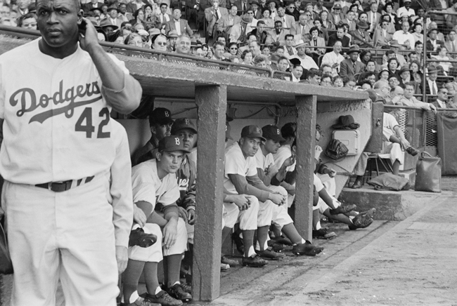 Jackie Robinson fica perto do abrigo durante um jogo com o Brooklyn Dodgers