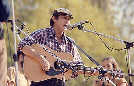 Phil Ochs Tocando Guitarra. Imagem de Mark Sarfati, 1975, Cortesia de Mark Sarfati.