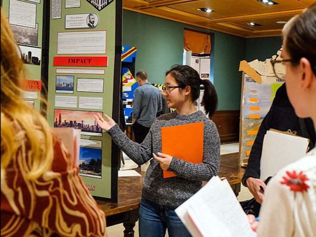 A student stands in front of her History Day project display. 