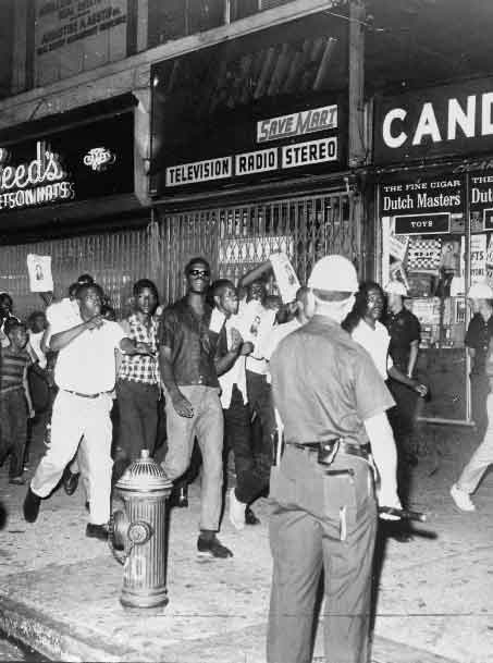鲍威尔的致命枪击事件激起了黑人骚乱者携带吉利根中尉的照片穿过哈莱姆街道
