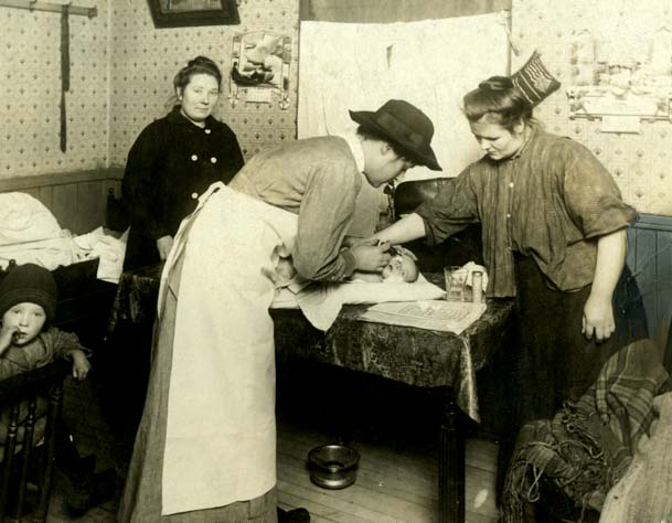 Une infirmière visiteuse de Henry Street Settlement traite un bébé dans un immeuble