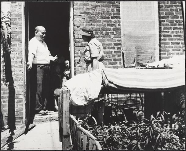 Service d'infirmières itinérantes de la rue Henry, à l'arrière de la lessive chinoise, le père salue l'infirmière lors d'une visite de routine pour voir son enfant