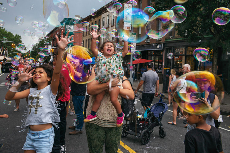 Membros da comunidade Park Slope na rua brincando com bolhas.