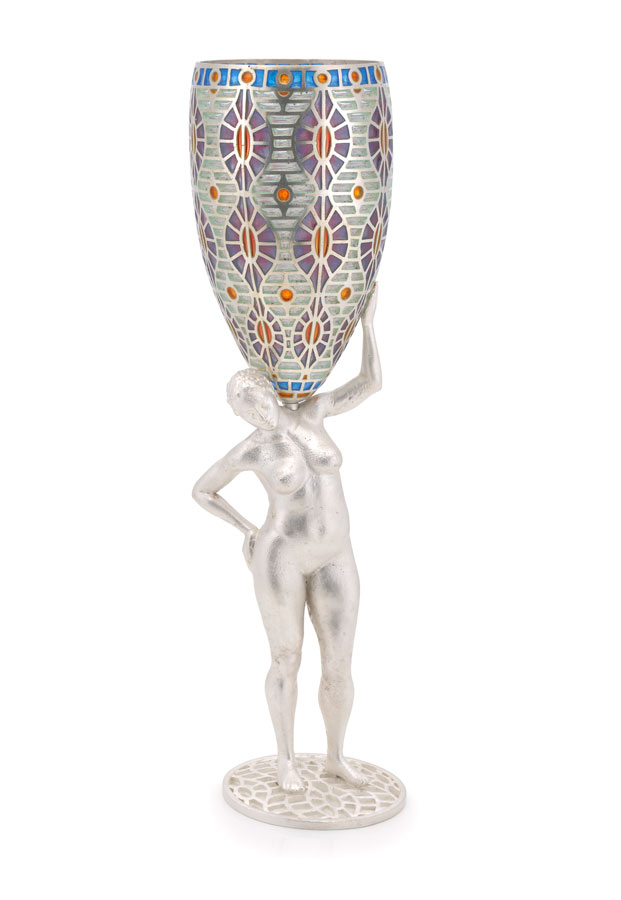 Un grand verre à vin avec un motif peint coloré sur le verre. La tige du verre est une statuette en argent d'une femme nue