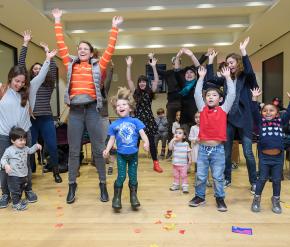 A group of adults and children jump. 