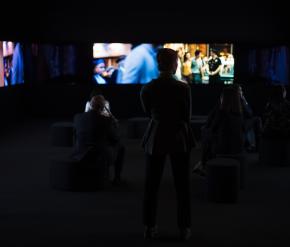 La silhouette d’une femme debout devant plusieurs écrans montrant des images floues de films.